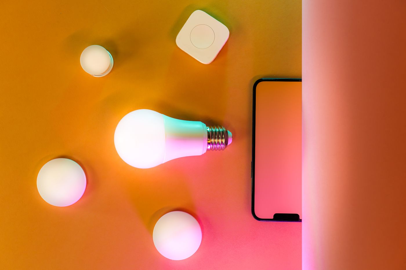 A smart light bulb beside wireless lighting accessories