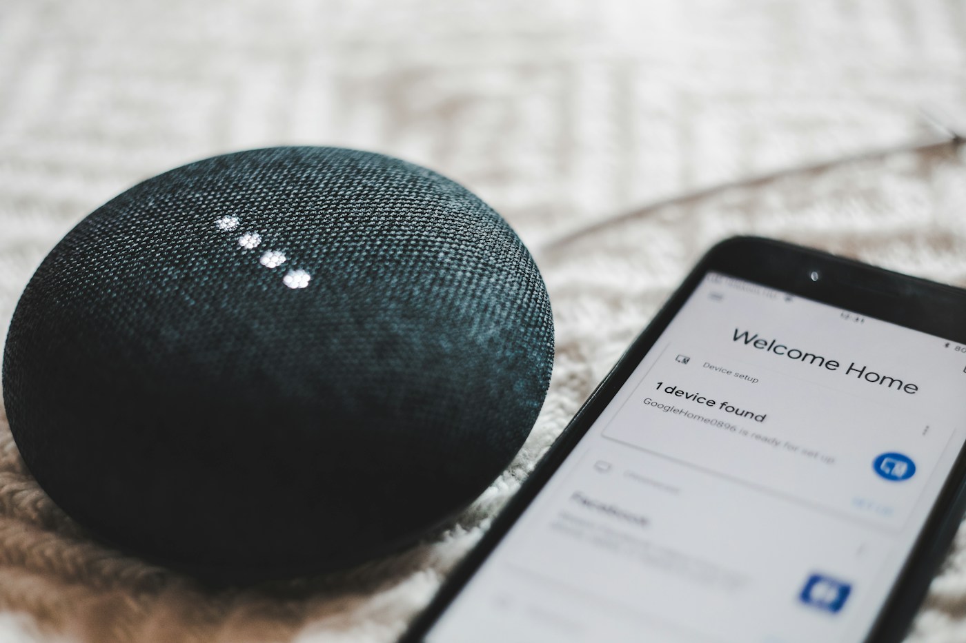 A phone showing the setup app beside a smart speaker