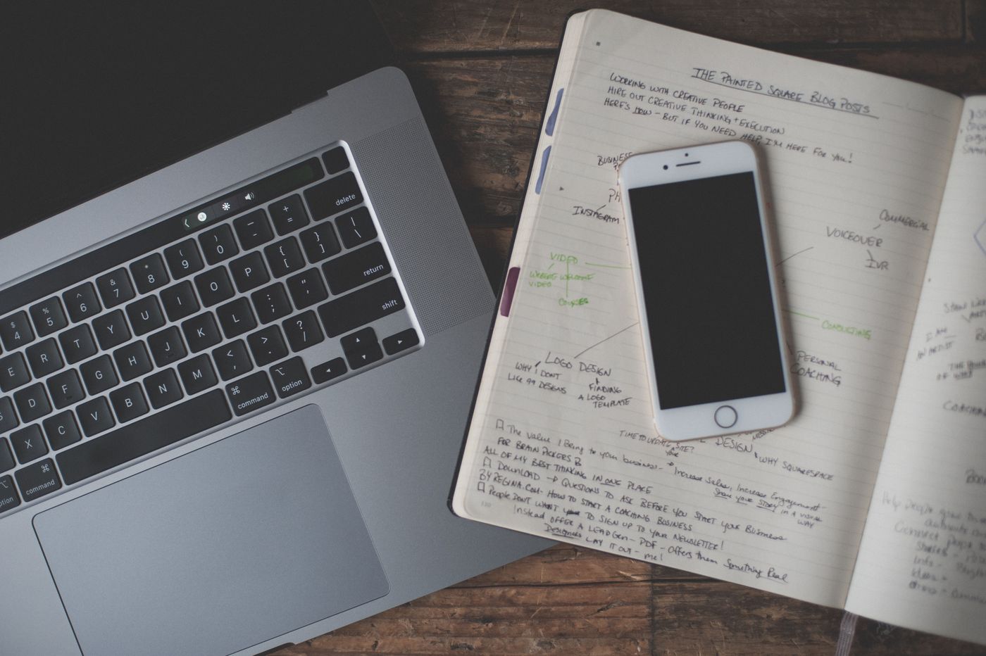 Phone and open notebook beside a laptop