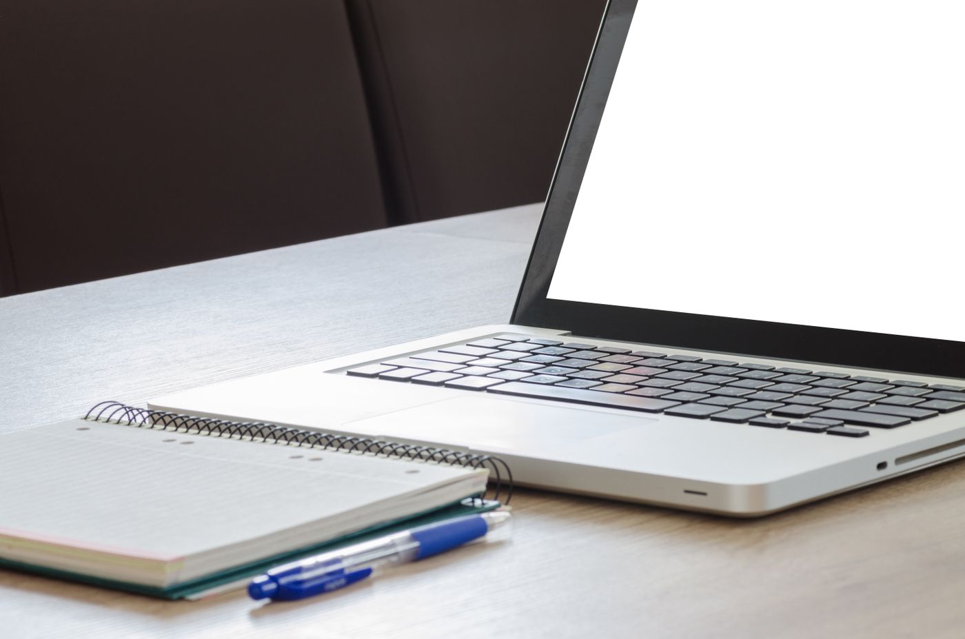 Open notebook and pen beside a laptop