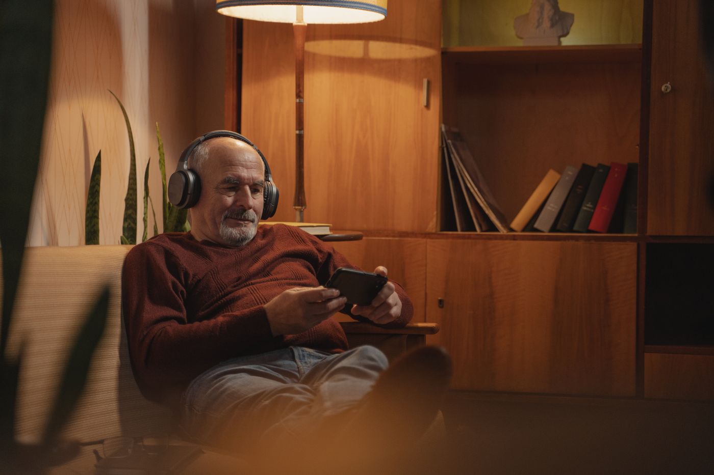 Person using wireless headphones and a phone in a living room