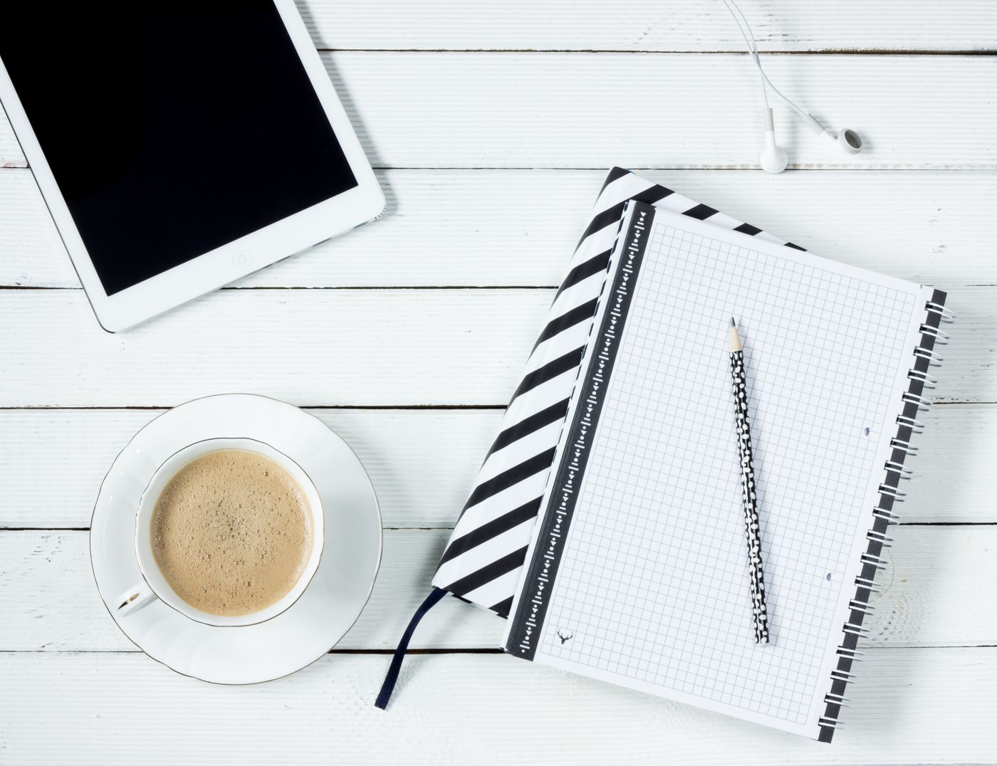 Tablet beside a notebook and pencil